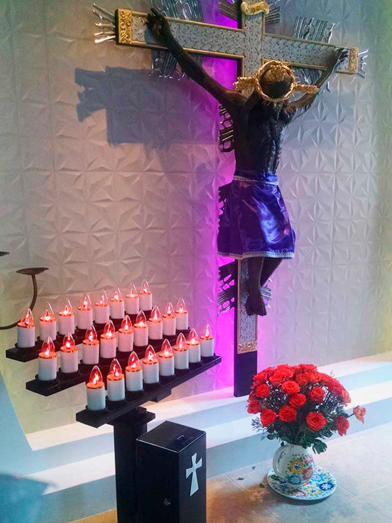 Lamparario de 27 velas ante una imagen de Cristo crucificado