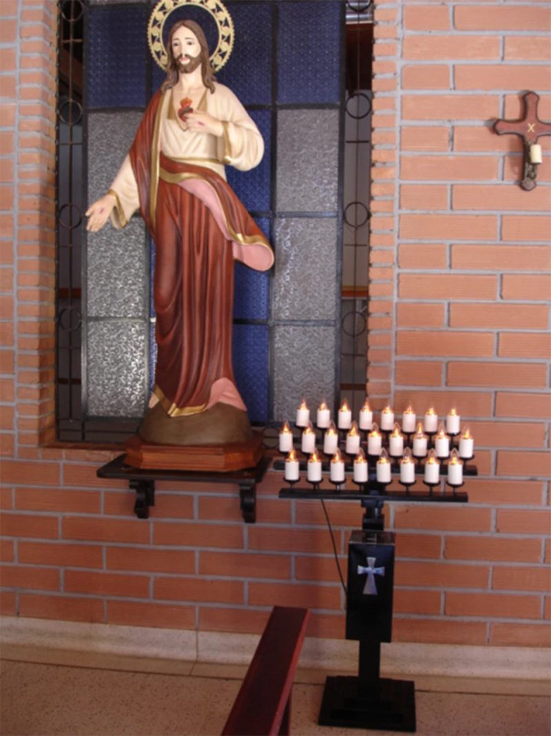 Lamparario de hierro de 25 velas junto a la imagen del Sagrado Corazón