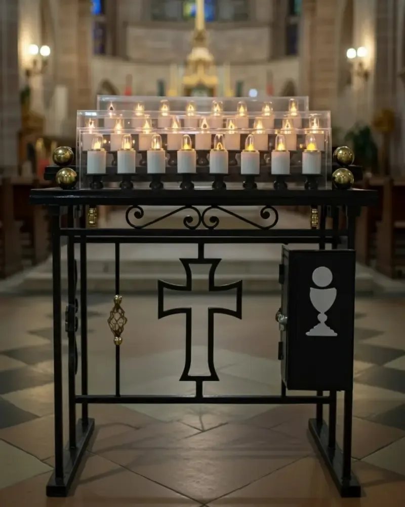 Lamparario electrónico en hierro forjado con tres líneas de velas, cruz y alcancía, en una iglesia